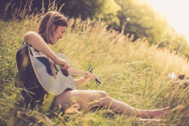 Güzel bir kadın açık havada klasik gitar çalar.