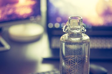 Bilgisayar ve dizüstü bilgisayar ve masada bir şişe su.