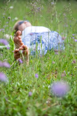 Genç bir kadın yeşil çimlerde yatıyor.