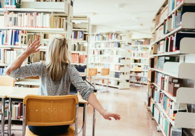 Kütüphanede dizüstü bilgisayarda çalışan bir kadın.