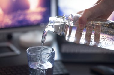 Kırpılmış insan görüntüsü bardağa su döküyor. 