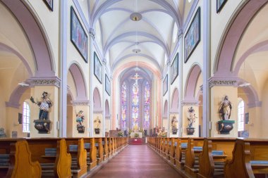 Büyük, modern bir kilisenin içinde sıralar ve haçlar görünür. 