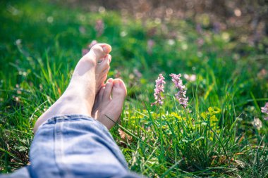 Erkek bacakları yeşil çimlerde yatıyor.