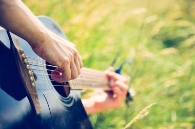 Adam açık havada klasik gitar çalıyor.