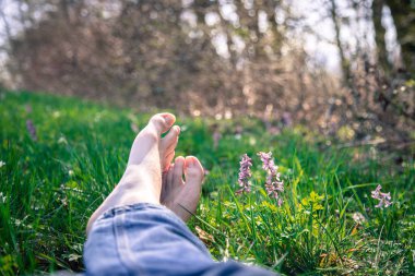 Erkek bacakları yeşil çimlerde yatıyor.