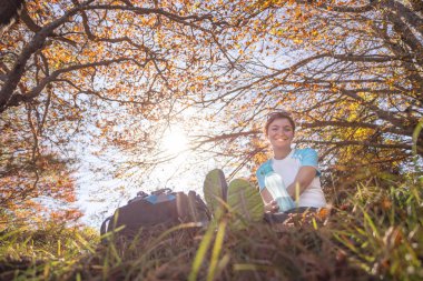 Sırt çantalı dağcı ormanda oturuyor.