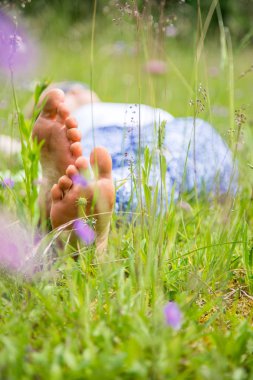 Genç bir kadın yeşil çimlerde yatıyor.