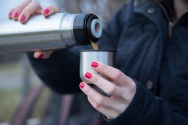 Kışın termostan sıcak su içen kadın. 