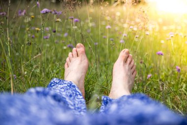 Kadın bacakları yeşil çimlerde yatıyor.