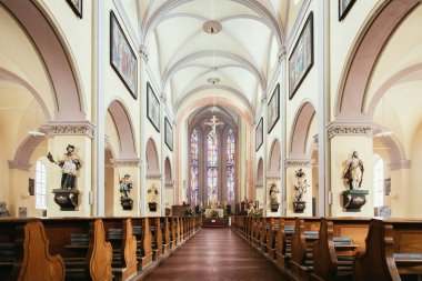 Büyük, modern bir kilisenin içinde sıralar ve haçlar görünür. 