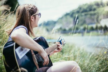 Güzel bir kadın açık havada klasik gitar çalar.