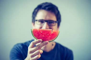 Gözlüklü yakışıklı genç adam karpuz yiyor.