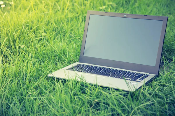 Close up laptop pc computer  on green grass