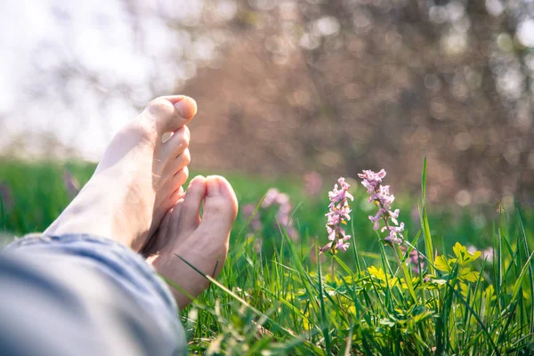 Erkek bacakları yeşil çimlerde yatıyor.