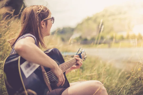 Güzel bir kadın açık havada klasik gitar çalar.