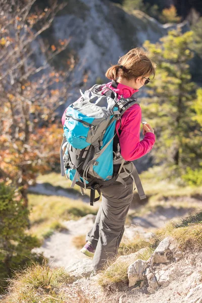 年轻的女徒步旅行者爬上山顶悬崖上的岩石 — 图库照片