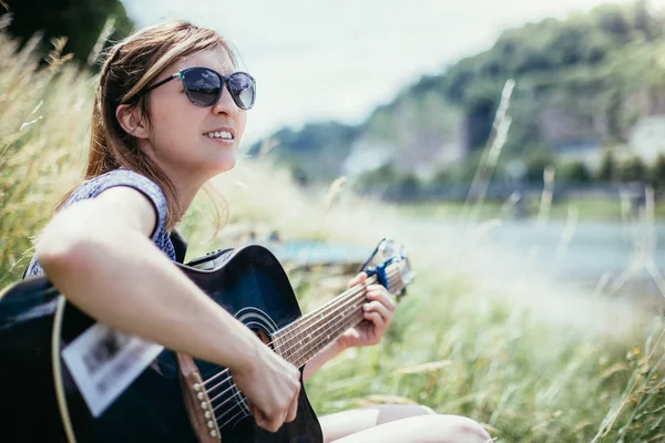 Güzel bir kadın açık havada klasik gitar çalar.
