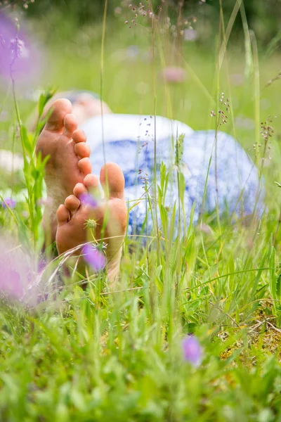 Genç bir kadın yeşil çimlerde yatıyor.