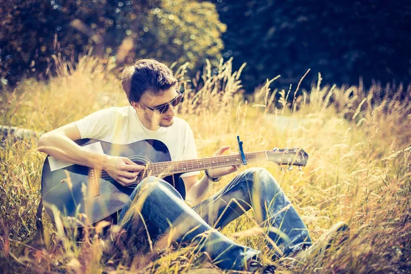 Yakışıklı adam açık havada klasik gitar çalıyor.