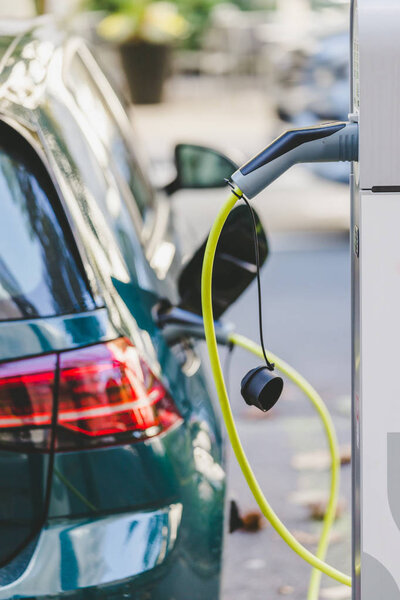 Электрическая подзарядка автомобиля с помощью кабеля и разъема, ведущего к точке зарядки
