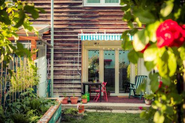 Kırmızı gül çiçekleri ve arka planda yükseltilmiş küçük bir bahçe.