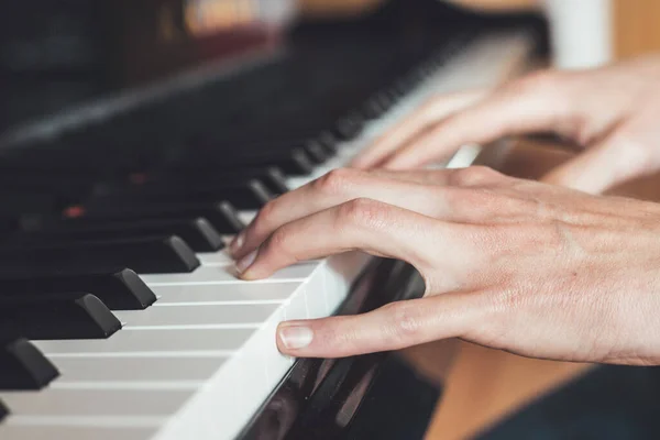 Man is playing piano at home. Clipping of piano and hands.