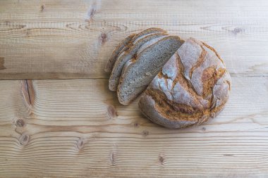 Dilimlenmiş taze siyah ekmek, tahta bir kesme tahtasının üzerinde yatıyor.. 