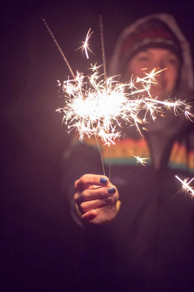 微笑的女孩手里拿着一个闪烁着火花的人 新年来到了户外 — 图库照片