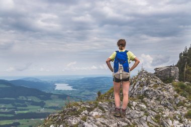 Genç, sıska sırt çantalı turist kız Avusturya 'nın kayalık dağındaki manzaranın tadını çıkarıyor.