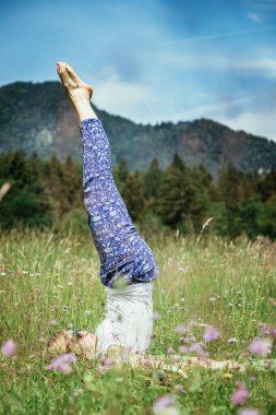 Genç kız parkta yoga yapıyor. 