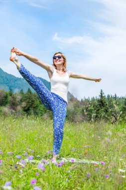 Genç kız parkta yoga yapıyor. 