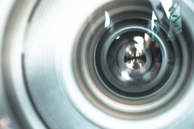 Fotoğrafçı elinde profesyonel bir fotoğraf optiği tutuyor. Bulanık arkaplanda dizüstü bilgisayar. 