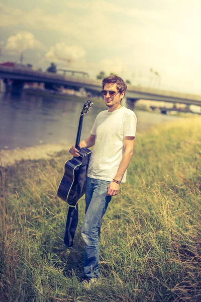 Joven Está Sentado Río Tocando Guitarra Occidental —  Fotos de Stock