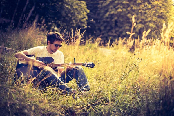 Jovem Está Sentado Rio Tocando Sua Guitarra Ocidental — Fotografia de Stock