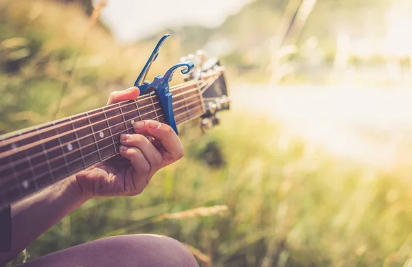 Close up of western guitar played outdoors at a river, summertime