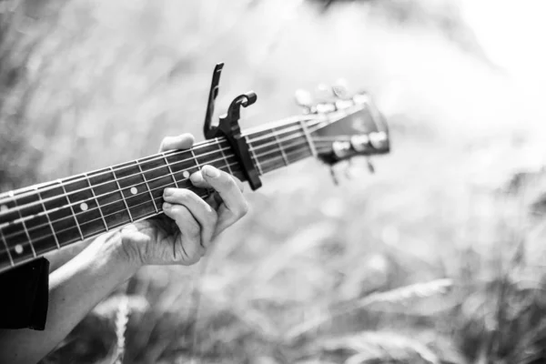 Close up of western guitar played outdoors at a river, summertime