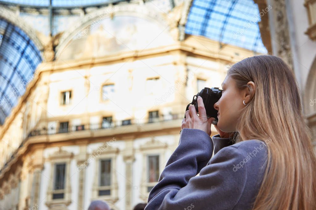 Tourist girl takes a photo in Galleria Vittorio Emanuele II during the day in Milan Italy