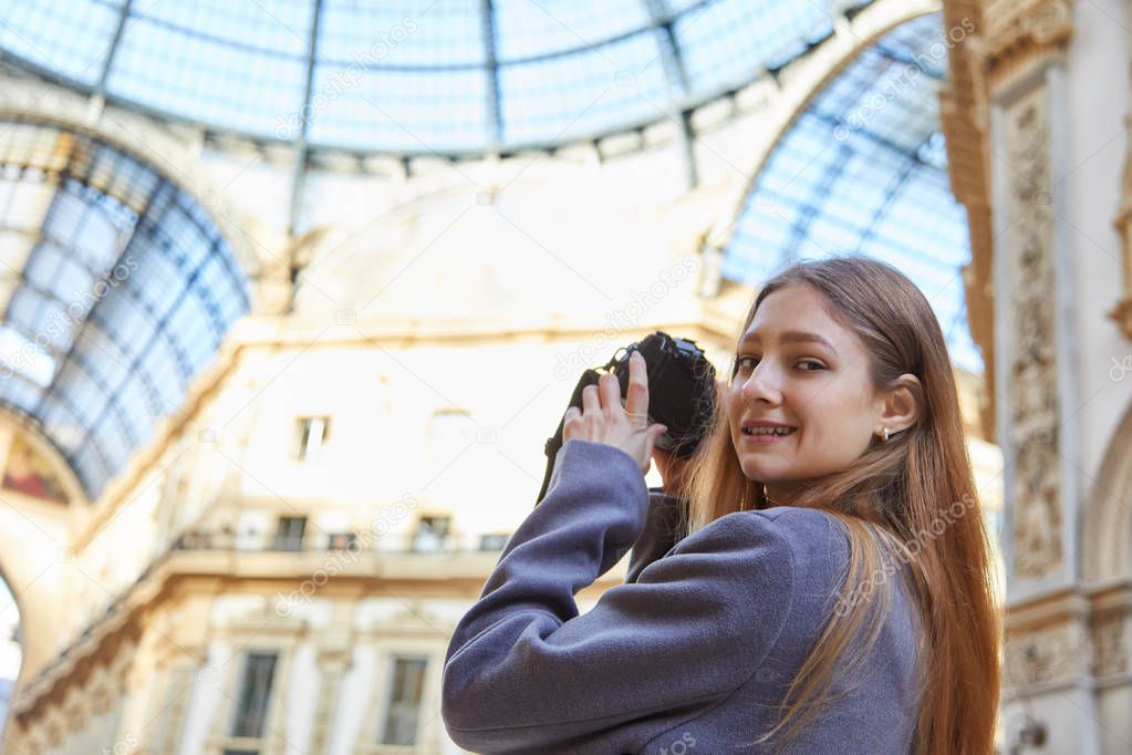 Tourist girl smile and takes a photo in Galleria Vittorio Emanuele II during the day in Milan Italy