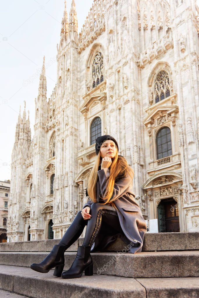 Pensative Girl sitting in front of Duomo of Milan vertical crop
