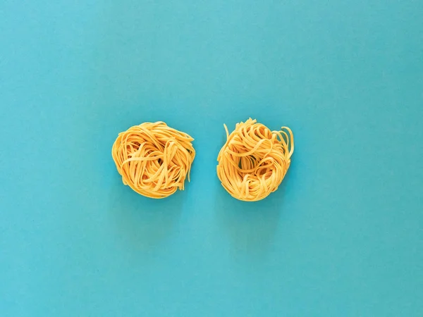 Italian noodle pasta uncooked over cyan background in studio from top view. — Stock Photo, Image
