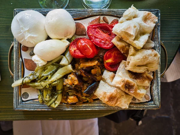 Schneidebrett mit Focaccia, Tomaten, Mozarella, Burrata und Antipasto. — Stockfoto