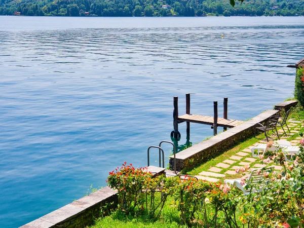 Muelle de madera rodeado por un jardín en la orta lago italia durante — Foto de Stock