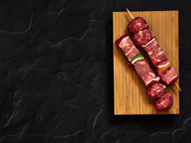 pişmemiş sığır şişleri yukarıdan aşağıya görünümü karanlık bir arka plan ile ahşap bir tahta üzerinde izole