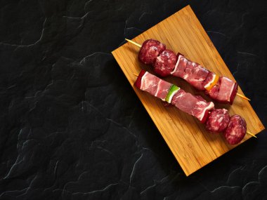 pişmemiş sığır şişleri yukarıdan aşağıya görünümü karanlık bir arka plan ile ahşap bir tahta üzerinde izole