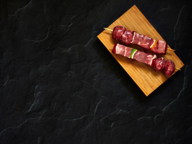 pişmemiş sığır şişleri yukarıdan aşağıya görünümü karanlık bir arka plan ile ahşap bir tahta üzerinde izole