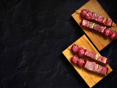 pişmemiş sığır şişleri yukarıdan aşağıya görünümü karanlık bir arka plan ile ahşap bir tahta üzerinde izole