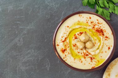 Ev yapımı nohut humus kase haşlanmış nohut, otlar, zeytin yağı ve gri arka plan üzerinde pide ile dekore edilmiştir. Üstten Görünüm, düz yatıyordu, kopya alanı.