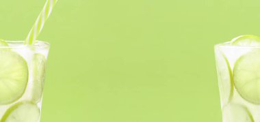 Yeşil arka planda saman içen buz camında donmuş kireç dilimleri. Soğuk buzlu içecek, yaz narenciye kokteyli. Kopyalama alanı