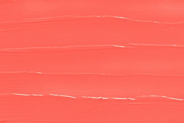 Coral lipstick texture. Smudged makeup cosmetic liquid in trendy color abstract background.