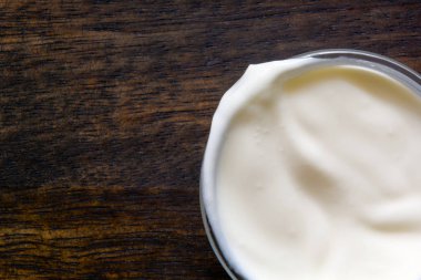 Ahşap arka planda yoğurt veya ekşi krema kase